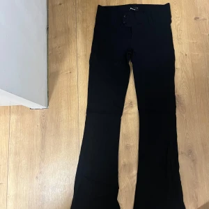 Svarta bootcut-byxor Gina Tricot - Snygga svarta bootcut-byxor från Gina Tricot i storlek 36. Byxorna har hög midja, stängs med knappar och dragkedja framtill och är tillverkade i ett mjukt material med stretch. Perfekta för en clean och stilren look. Nya aldrig använda 