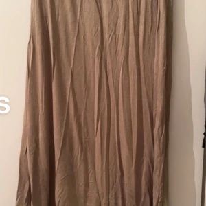 Beige långkjol i luftig bomull - En stilren beige långkjol i mjukt och luftigt bomullstyg. Kjolen har en rak och enkel design som gör den lätt att matcha med olika toppar och accessoarer. Perfekt för dig som gillar en avslappnad och trendig look.🌸Fint använt skick. Storlek s