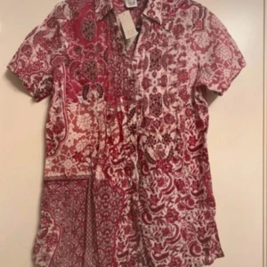 skjorta - Säljer en helt ny skjorta i vinrött och vitt mönster – riktigt fin färgkombination! 📏 Storlek: 34/36 👘 Korta ärmar i vinröd nyans med blommigt mönster ❄️ Lätt, luftig och perfekt för vår/sommar 🎀 Prislappen sitter kvar (utan pris) 💯 Aldrig använd  En mjuk, sval skjorta som är både stilren och bekväm!