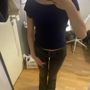 Mörkblå topp med spetsdetaljer - Säljer en mörkblå topp med korta ärmar och fina spetsdetaljer vid halsringning och ärmslut. Modellen croppad, perfekt till jeans eller kjol. Toppens material känns mjukt och stretchigt, vilket gör den superbekväm att bära. Helt ny, aldrig använt! Köpt från shein.