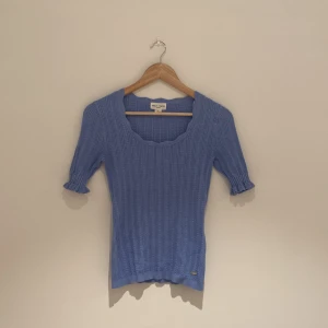 Blå stickad topp Holly & Whyte - Supersöt ljusblå stickad topp från Holly & Whyte med ribbat mönster, rundad urringning och korta ärmar med volangkant. 💕😍Perfekt för vår och sommar, passar till både jeans och kjol. ☀️Materialet är mjukt och stretchigt. Storlek S. Kommer i jätte bra skick!💙🤍