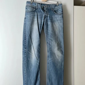 Tom Smith jeans  - Snygga jeans från Tom Smith Denim med slitna detaljer och klassisk femficksdesign. Jeansen har raka ben och coola kontrastsömmar, samt rutigt tyg på insidan av gylfen. Perfekta för en avslappnad stil.