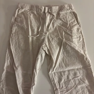 Beiga linnebyxor från H&M med snörning - Luftiga beiga linnebyxor från H&M i regular fit. Byxorna har elastisk midja med snörning och sidfickor, samt en bakficka. Perfekta för varma dagar när du vill ha en chill och avslappnad stil.