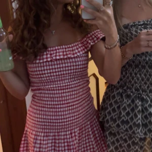 Rödvit rutig kortklänning med volang - Supersöt kortklänning i rödvitt rutigt mönster med smockad överdel och volang vid axlarna. Klänningen har en offshoulder-look och är perfekt för sommardagar. Materialet känns lätt och luftigt, och passformen är figurnära upptill med utsvängd kjol. Jag har vanligtvis cs och s men den är väldigt sretchigt material så den passar många storlekar