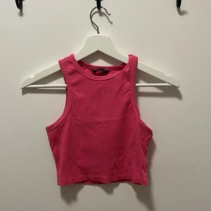 Rosa croppad linnetopp - En enkel och snygg rosa croppad linnetopp med breda axelband och rund halsringning. Perfekt för varma dagar eller att styla lager på lager. Mjuk bomullskänsla och stilren design som passar till jeans eller kjol.