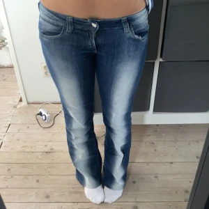 Blå bootcut jeans från Cheap Monday - Snygga blå bootcut jeans från Cheap Monday med coola slitningar och klassisk femficksmodell. Jeansen har låg midja och är tillverkade i mjukt denimtyg. Perfekta för dig som gillar en avslappnad men trendig look. Jeansen är uppsydda längst ner vid byxbenen, inget som syns. Skulle säga att byxan passar för de som är runt 160-166 cm.