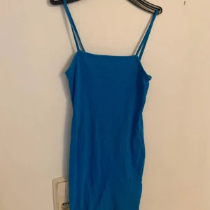 Blå ribbad kortklänning från MISU - Säljer en blå ribbad kortklänning från MISU med smala axelband och rak halsringning. Klänningen har en tight passform och är perfekt för dig som gillar en enkel men snygg look. Materialet är mjukt och stretchigt för extra komfort.