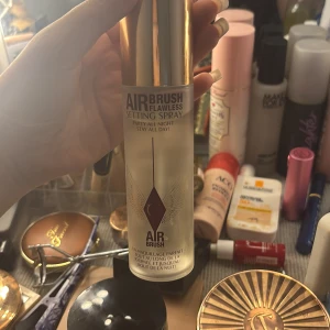 Charlotte Tilbury Airbrush Setting Spray - Airbrush Flawless Setting Spray från Charlotte Tilbury i en genomskinlig flaska med guldig kork. Perfekt för att fixera sminket hela dagen och natten. Ger en fräsch finish och håller makeupen på plats utan att kännas tung. Finns förpackning 