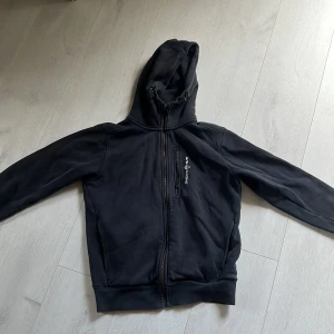 Svart hoodie Sail Racing - Svart hoodiejacka från Sail Racing. Använd men bra mycket bra skick.