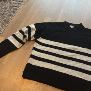 Randig svartvit stickad tröja Gina Tricot - Snygg stickad tröja från Gina Tricot i svart och vitt med breda horisontella ränder. Tröjan har rund halsringning och långa ärmar. Perfekt för dig som gillar en klassisk men ändå trendig look.