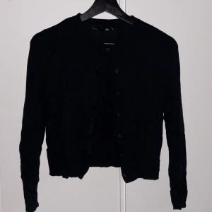 Svart kofta från lager 157, XS - Svart kofta från lager 157 i storlek XS. Klassisk modell med rund halsringning, knappar framtill och långa ärmar. 