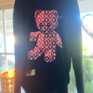 Philipp Plein svart hoodie med teddy - 16000kr ny pris!! nyTeddy Bear långärmad hoodie Kolsvart, bomullsblandning, jersey-stickning, ribbade detaljer, applikation, broderad logotyp baktill, tryckt slogan på sidan, rymlig huva med dragsko, långa ärmar, rak fåll. Tröjan är helt i nyskick, endast testad en gång. Men känner att den förtjänar att se lite dags ljus i ett annat hem istället föratt bara hänga i garderoben. Material. Yttre: bomull 100% Foder: polyester 100%  Säljes eller bytes mot en snygg jacka eller väst i samma prisklass. 