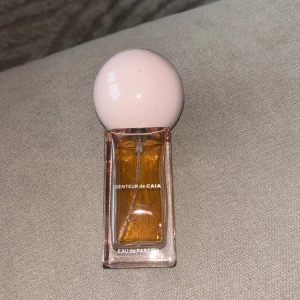Senteur de Caia Eau de Parfum - Parfymflaska från Caia med namnet Senteur de Caia. Flaskan är rektangulär i genomskinligt glas med en ljusrosa, rund kork. Innehållet är bärnstensfärgat och ger en lyxig känsla. Perfekt för dig som gillar snygg design och vill ha en trendig parfym på hyllan. Den är använd som ni ser, därav bra pris!💗