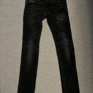 Svarta Diesel Sleenker skinny jeans - Svarta skinny jeans från Diesel, modell Sleenker. Jeansen har en tight passform med stretchigt material för extra komfort. Klassisk femficksdesign och diskreta slitningar framtill för en cool look.