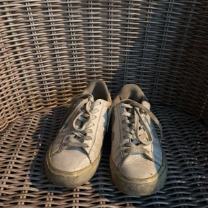 Vita sneakers från Veja i skinn - Klassiska vita sneakers från Veja med grå detaljer och snörning. Skorna har rund tå, platt sula och är tillverkade i skinn med V-logga på sidan och Veja-tryck på hälen. Köpta för 1700kr. GÅR STT GÖRA RENT