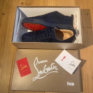  Christian Louboutin - Snygga mörkblå sneakers från Christian Louboutin i mjuk mocka med klassisk röd sula. Skorna har rund tå, platt sula och snörning framtill. Broderad Louboutin-logga baktill och lyxig känsla med beige innersida. Perfekta för dig som vill sticka ut med exklusiva detaljer. Det är okej att pruta om man vill. Först till Kvarn!
