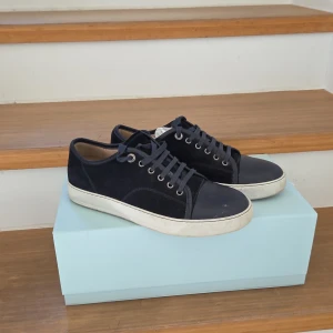 Mörkblå sneakers från Lanvin - Snygga mörkblå sneakers från Lanvin med ovandel i mocka och tåparti i skinn. Klassisk design med vita sulor och mörkblå snörning. Perfekta för dig som gillar stilrena och exklusiva sneakers med en lyxig känsla.