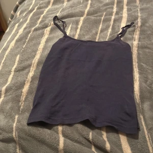 Mörkblå linnetopp från H&M - En enkel och stilren mörkblå linnetopp från H&M med smala axelband. Toppen är i mjuk bomull och har en rak passform som är perfekt till jeans eller kjol. Snygg att bära som den är eller under en skjorta.