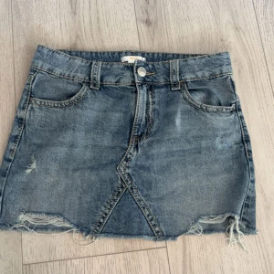 Jeanskjol från Gina Tricot - Snygg blå jeanskjol från Gina med knappar på bakfickorna. Använt 1 gång 