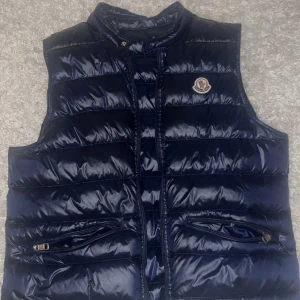 Marinblå moncler väst - Använd ett fåtal gånger storlek 2/m dem är lite små i storlekar så rekommenderar någon med en lite mindre storlek, väldigt bra skick, säljs pga att den inte passar. Pris kan diskuteras