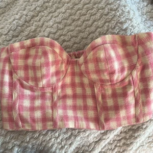 Rutig rosa korsettopp - Superfin croppad korsettopp från Zara i storlek XS med rutigt mönster i rosa och beige och ett stretchigt material i ryggen! Perfekt för sommaren! 💝 den här lite små lösa trådar på några ställen (skriv om ni vill ha bild) så därav det billiga priset! 🌷