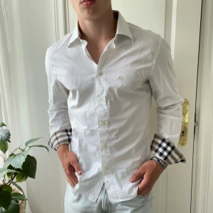 Vit Burberry skjorta - Väldigt najs passform, liten defekt i båda armhålorna där det finns svett fläckar. Märks knappt när du har på dig den. 👍 Modellen är 180,75 kg och bär L. 