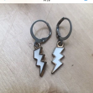 Örhängen med vita blixtar - Coola örhängen med vita blixtformade hängen och metallfärgade ringar. Blixtarna har en snygg kant i guldton som ger extra edge till din stil. Perfekta för dig som vill sticka ut med ett unikt smycke. Priset gäller för ett par och det finns 3 par i lager, man kan köpa alla 3 par för 10kr💞