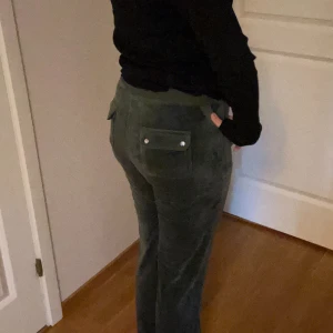 Mörkgröna mjukisbyxor Juicy Couture - Mörkgröna mjukisbyxor från Juicy Couture i mjuk frotté. Byxorna har raka ben, snörning i midjan och stora fickor både fram och bak med knappdetaljer. Perfekta för en chill och avslappnad stil. (Priset låg först på 600 när jag la ut annonsen men har valt att sänka priset till 300 och kan sänka ännu mer vid en snabb affär)