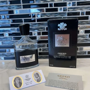 Creed Aventus Eau de Parfum 100ml - Lyxig parfym från Creed, Aventus, 100ml. Flaskan är transparent med svart och silverdetaljer, och har en svart kork med silveremblem. Kommer med originalkartong och äkthetskort. Doften är ikonisk och exklusiv, perfekt för dig som gillar eleganta och fräscha parfymer.