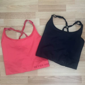 Better Bodies linne toppar med snörning - Två snygga linne toppar från Better Bodies, en i svart och en i stark rosa. Båda har smala axelband och cool snörningsdetalj i ryggen. Perfekta för träning eller när du vill ha en sportig vibe. Materialet är stretchigt och följsamt för maximal komfort.