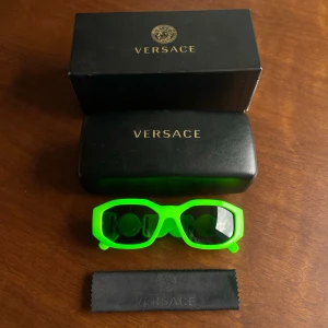 Solglasögon Versace  - Säljer ett par neongröna solglasögon från det italienska modehuset Versace. De är den älskade  modellen 4361 med de ikoniska guldiga Medusa-detaljerna på sidorna. Kommer med originaletui och putsduk. Väldigt sällsynt färg vilket gör det till ett statement-piece. Tips: Perfekt för festivaler i UV-ljus. Helt perfekt skick. Nypris 240eur.