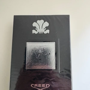 Creed Aventus parfym 100ml - Lyxig parfym från Creed, modellen Aventus. Förpackningen är svart med silverdetaljer och har en elegant metallplatta med en ryttare. Klassisk och exklusiv doft i stilren kartong, perfekt för dig som gillar premiumparfymer.