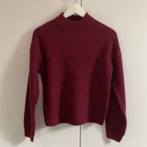 Vinröd stickad tröja - Snygg vinröd stickad tröja med hög krage och ribbade detaljer. Perfekt för sommarkvällar eller kallare dagar och enkel att matcha med jeans eller kjol. Långärmad och mjuk, passar dig som gillar en stilren look! Den är aldrig använd och har kvar prislapp! Köptes för 159kr men jag säljer för 95kr!
