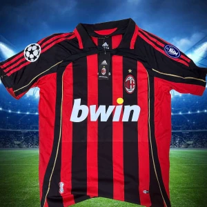 AC Milan Kaka' 22 Adidas matchtröja - AC Milan fotbollströja med Kaka' 22 på ryggen. Klassisk röd och svart randig design med guldiga detaljer och klubbmärke på bröstet. Adidas-logga, Champions League-märke på ärmen och Bwin som sponsor. Tillverkad i lätt och ventilerande material. Storlek S,M