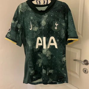 Tottenham Maddison #10 tredjeställ - Tottenham Hotspur replika tredje tröja med Maddison #10 på ryggen. Tröjan är mörkgrön med unikt abstrakt mönster, vita tryck och gula detaljer vid ärmslut. Tillverkad i lätt funktionsmaterial. Handtvätt rekommenderas!