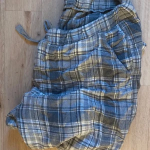 Gråblå rutiga shorts med snörning - Rutiga shorts i grått och blått med snörning i midjan. Mjukt och lätt material, perfekt för chill dagar. Klassisk loose fit och avslappnad stil.