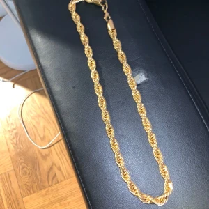 Guld halsband - Säljer ett snyggt guldfärgat halsband med tvinnad kedja, Cordell. Kedjan är 10mm bred och 60cm lång. Och 18k guldplaterad.