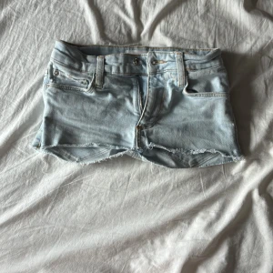 Ljusblå jeansshorts från MNG - Snygga ljusblå jeansshorts från MNG med råa, fransiga kanter och klassisk femficksdesign. Shortsen har gylf med dragkedja och knapp, bälteshällor och är perfekta för varma dagar. Superenkel och clean look som passar till allt.
