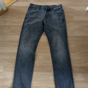 Grå jeansbyxor i slim fit, 29/30 - Snygga grå jeansbyxor med slitna detaljer och klassisk femficksdesign. Modellen är slim fit med normal midja och raka ben. Perfekta för dig som gillar en stilren och avslappnad look. Materialet är mjukt och följsamt jeans.