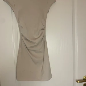 Beige kortklänning från Zara - En stilren beige kortklänning från Zara i figurnära modell. Klänningen har korta ärmar och är tillverkad i ett mjukt, stretchigt material som sitter snyggt på kroppen. Perfekt för dig som gillar en enkel men trendig look.