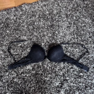 Svart BH från Gekås - Säljer en svart BH från Gekås i storlek 75C. Toppen har snygg spetsdetalj över hela och är axelbandslös, perfekt för en trendig look. Mjuk och bekväm passform som sitter snyggt på kroppen.