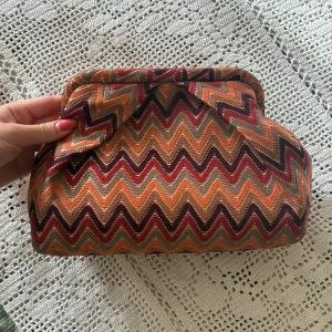Mönstrad clutch från Beck Söndergaard - Snygg eftertraktad bonita clutch från Beck Söndergaard med  zickzackmönster som inte längre säljs, har en innerficka. Superbra skick utan några anmärkningar. Säljer samma väska på vinted under samma användarnamn om man hellre köper därifrån 🌷💗