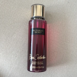 Victoria's Secret Pure Seduction mist - Fräsch och fruktig body mist från Victoria's Secret i doften Pure Seduction. Flaskan är genomskinlig med rödrosa vätska och har guldfärgat lock. Rymmer 250 ml och är perfekt att spraya på kroppen för en söt och fräsch känsla.