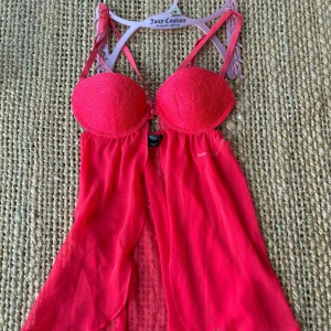 Röd spetsig babydoll från Victoria's Secret - Säljer en röd babydoll från Victoria's Secret med vadderade kupor och spetsdetaljer upptill. Toppen har tunna axelband och ett luftigt, transparent tyg som faller snyggt. Perfekt för dig som gillar en feminin look.