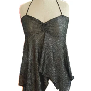 Glittrig silver halterneck topp - Supersnygg hemmasydd glittrig silverfärgad halterneck topp med lätt utsvängd och asymmetrisk nederdel. Tunn och luftig med smala band som knyts i nacken. Perfekt för dig som vill sticka ut med en cool och trendig look.