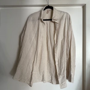 Beige linneskjorta från Nelly - Säljer en stilren beige skjorta från Nelly i storlek 34. Skjortan är tillverkad i linne, har klassisk krage, långa ärmar och knäppning framtill. Perfekt för en avslappnad och trendig look under varmare dagar.