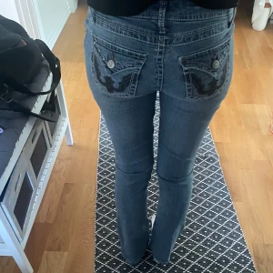 Blå bootcut jeans med broderade bakfickor och diamanter - Säljer ett par lågmidjade blå jeans med snygga broderade detaljer på bakfickorna och diamantstenar både fram och bak. Köpta på A2 vintage men märket är Mudd💕 
