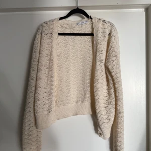 Beige stickad kofta från MNG - Snygg beige stickad kofta från MNG i storlek M. Koftan har ett luftigt, virkat mönster och långa ärmar med ribbade muddar. Perfekt att slänga över en topp för en chill och trendig look.