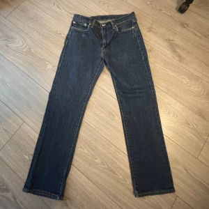 Levi's 514 mörkblå jeans straight fit - Klassiska Levi's 514 jeans i mörkblå denim med raka ben och normal passform. Byxorna har fem fickor, knappgylf och den ikoniska läderpatchen bak i midjan. Perfekta för dig som gillar tidlös stil och vill ha ett par jeans som funkar till allt.