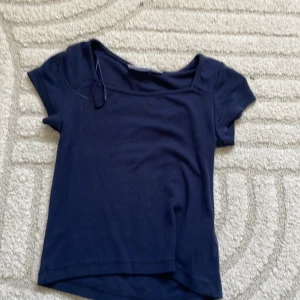 Mörkblå croppad topp - En enkel och stilren mörkblå croppad topp med korta ärmar och rund halsringning. Perfekt att matcha med jeans eller kjol för en avslappnad look. Mjuk och skön i materialet, passar till både vår och sommar.